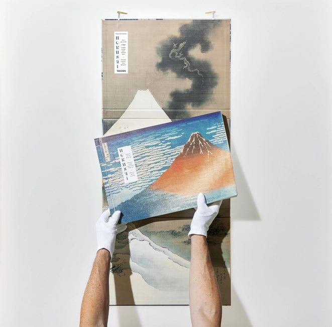 White gloves packaging the book inside an illustrated box.