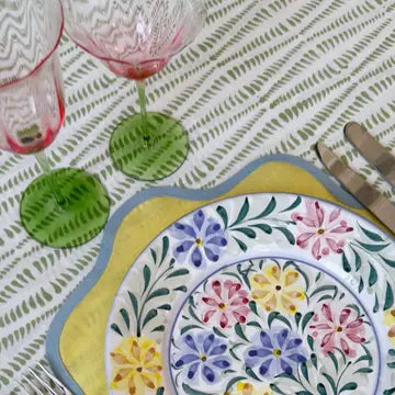 Decorative plate with floral design on a tablecloth with patterned tablecloth