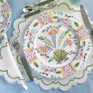 Decorative table setting with floral-patterned plates and cutlery on a matching placemat.